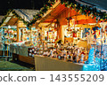 Illuminated Christmas market stall with handmade decorations and gifts, in Asti, Italy. 143555209