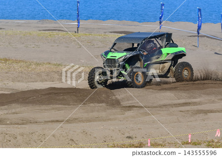 A green buggy car races down a dirt track, kicking up dust. A green buggy car races down a dirt track, kicking up dust. 143555596