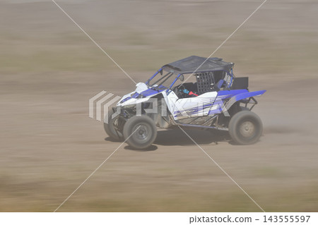 一輛藍白相間的越野車飛馳在塵土飛揚的土路上。 一輛藍白相間的越野車飛馳在塵土飛揚的土路上。 143555597