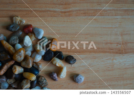 Colorful polished river pebbles arranged at the corner of wooden background Colorful polished river pebbles arranged at the corner of wooden background 143556507