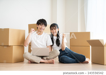 一對年輕夫婦在搬家時正在檢查電腦。 一對年輕夫婦在搬家時正在檢查電腦。 143556542