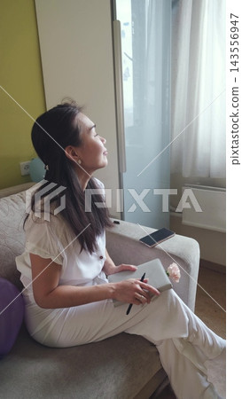 Thoughtful woman looking away from her journal. Inspiration, dreams and inner dialogue. 143556947