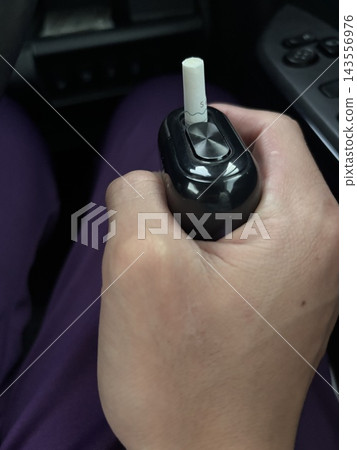 車內,一名男子的手拿著電子煙。 車內,一名男子的手拿著電子煙。 143556976