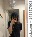 一名男子戴著桑拿帽，對著鏡子拿著智慧型手機。 143557008