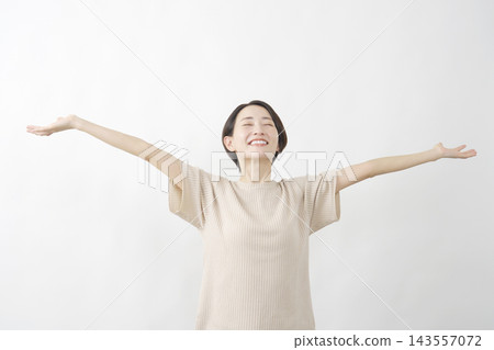 一名女子張開雙臂，在白色背景前深吸一口氣。 143557072