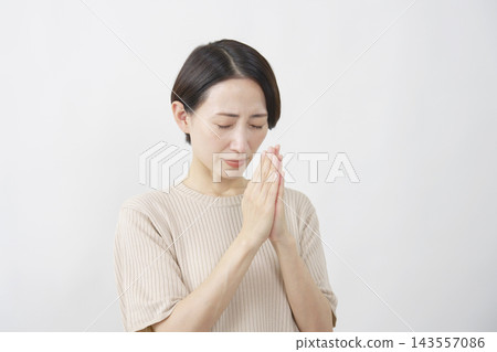 A woman in her 40s earnestly making a wish against a white background. A woman in her 40s earnestly making a wish against a white background. 143557086