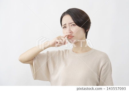 一位四十多歲的女性，在白色背景下，因鼻塞而感到不適。 143557093