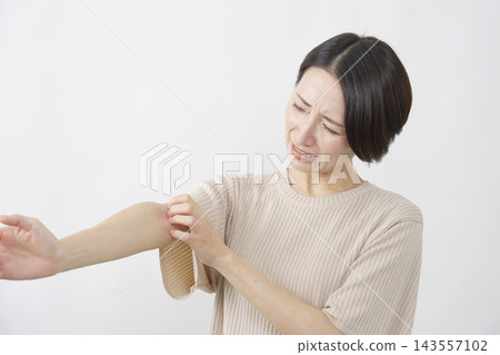 一位四十多歲的女性，在白色背景下，手臂發癢。 143557102