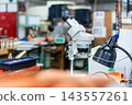 A microscope placed in a factory. Research and development, manufacturing, inspection, quality control, small factory, SME, maintenance, warehouse, equipment, industry, repair. 143557261
