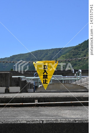 A yellow "No Entry" sign stands against a backdrop of blue sky and mountain ranges. A yellow "No Entry" sign stands against a backdrop of blue sky and mountain ranges. 143557541