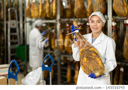 In jamon production shop, girl employee demonstrates final product In jamon production shop, girl employee demonstrates final product 143558745