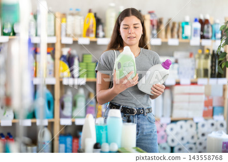 Young woman buyer chooses detergent in store 143558768