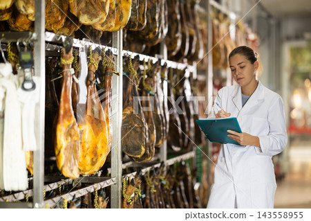 Female worker counts the amount of jamon in workshop Female worker counts the amount of jamon in workshop 143558955