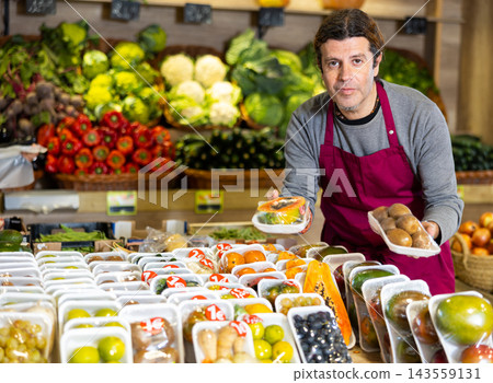 Adult man selling papaya and kiwi fruit in shop Adult man selling papaya and kiwi fruit in shop 143559131