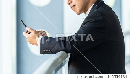 老年男性商務人士一邊看著智慧型手機一邊思考 143559184