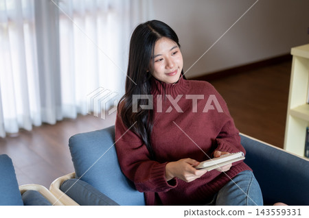 Asian Woman Holding Notebook and Looking Away Dreamily Asian Woman Holding Notebook and Looking Away Dreamily 143559331