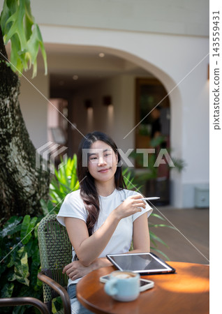 Asian Woman with Tablet and Coffee Gesturing with Stylus Outdoors 143559431