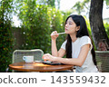 Asian Woman Leaning on Hand Thinking with Stylus at Garden Table 143559432