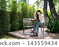 Asian Woman Studying with Digital Tablet at Outdoor Cafe Garden 143559434