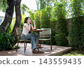 Asian Woman Leaning on Table Daydreaming with Stylus Outdoors 143559435