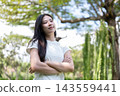Asian Woman Standing with Crossed Arms Looking Confident in Park 143559441