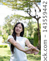 Asian Woman Stretching Arms and Warming Up Outdoors in Park 143559442