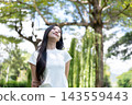Asian Woman Looking Up with Gentle Smile Outdoors in Nature 143559443