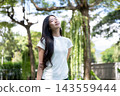 Asian Woman Breathing Fresh Air with Eyes Closed in Park 143559444