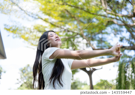 Asian Woman Stretching Arms Forward with Closed Eyes in Nature Asian Woman Stretching Arms Forward with Closed Eyes in Nature 143559447