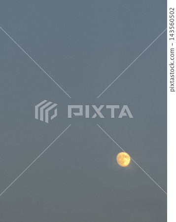 一輪黃色的月亮漂浮在藍灰色的天空和廣闊的空曠宇宙中。 一輪黃色的月亮漂浮在藍灰色的天空和廣闊的空曠宇宙中。 143560502