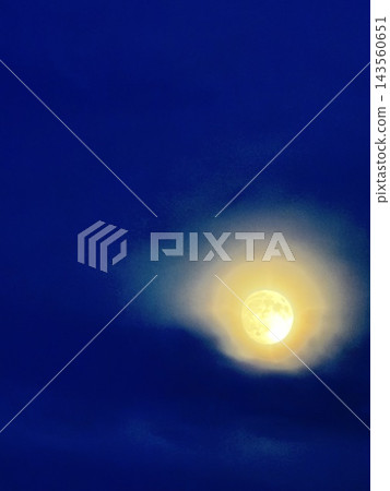 月亮懸掛在深藍色的夜空中,薄薄的雲層被它的光芒照亮。 月亮懸掛在深藍色的夜空中,薄薄的雲層被它的光芒照亮。 143560651