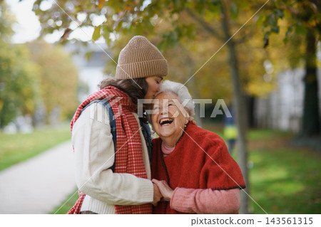 Portrait of a granddaughter on an autumn walk in the park with her grandmother. Portrait of a granddaughter on an autumn walk in the park with her grandmother. 143561315