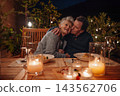 Senior couple enjoying romantic dinner together on terrace at night. 143562706