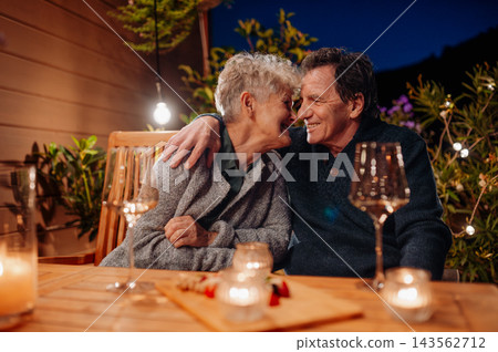 Loving senior couple enjoying romantic evening together on terrace. Loving senior couple enjoying romantic evening together on terrace. 143562712