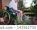 Senior man in wheelchair exercising with resistance band on terrace. 143562730