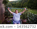 Senior man in wheelchair exercising with resistance band on terrace. 143562732