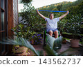 Senior man in wheelchair exercising with resistance band on terrace. 143562737