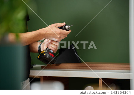 Man fitting drill bit into cordless drill before work Man fitting drill bit into cordless drill before work 143564364
