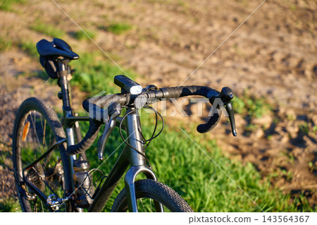 Gravel bike with front light parked beside field Gravel bike with front light parked beside field 143564367