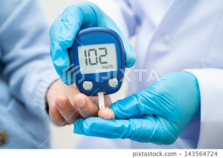 Asian doctor using digital glucose meter for check sample blood sugar level to treatment diabetes. Asian doctor using digital glucose meter for check sample blood sugar level to treatment diabetes. 143564724