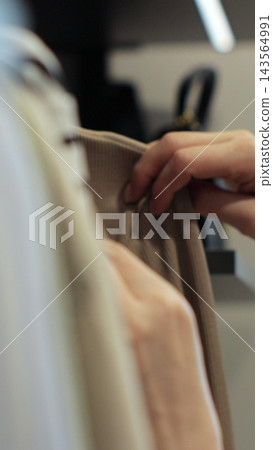 Vertical video. Close-up woman hand smoothing a colorful clothes. Clothing Store. Shopping. Vertical video. Close-up woman hand smoothing a colorful clothes. Clothing Store. Shopping. 143564991