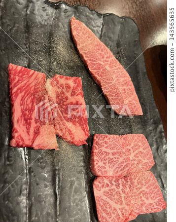 紋理優美的和牛烤肉,生食,盛放在黑色方盤中(用鹽和胡椒調味)。 紋理優美的和牛烤肉,生食,盛放在黑色方盤中(用鹽和胡椒調味)。 143565635