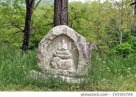 A roadside shrine surrounded by greenery A roadside shrine surrounded by greenery 143565769