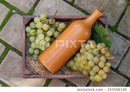 Ceramic Bottle and Grapes in a Wooden Crate, Top View Ceramic Bottle and Grapes in a Wooden Crate, Top View 143566180