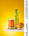 Beer mug with foam chips and bottle on yellow background snack setup 143566309