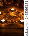 Sacred pentagram ritual circle with bird skull, burning candles, vintage key, feathers and herbs on witch wooden altar for Samhain, vertical image, film grain 143566381