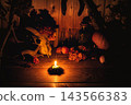 Mystical witch altar with animal horny skull, burning candle, pumpkin, autumn flowers and magical potion bottles in the dark for Samhain ritual, film grain 143566383