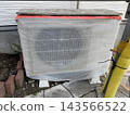 Air conditioner outdoor unit covered for protection during exterior wall painting work. 143566522