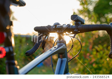 Gravel bike handlebars with front light at sunset Gravel bike handlebars with front light at sunset 143566524