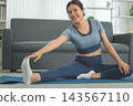 Active Asian Woman Exercising, Stretching and Tracking Fitness During a Healthy Home Workout 143567110